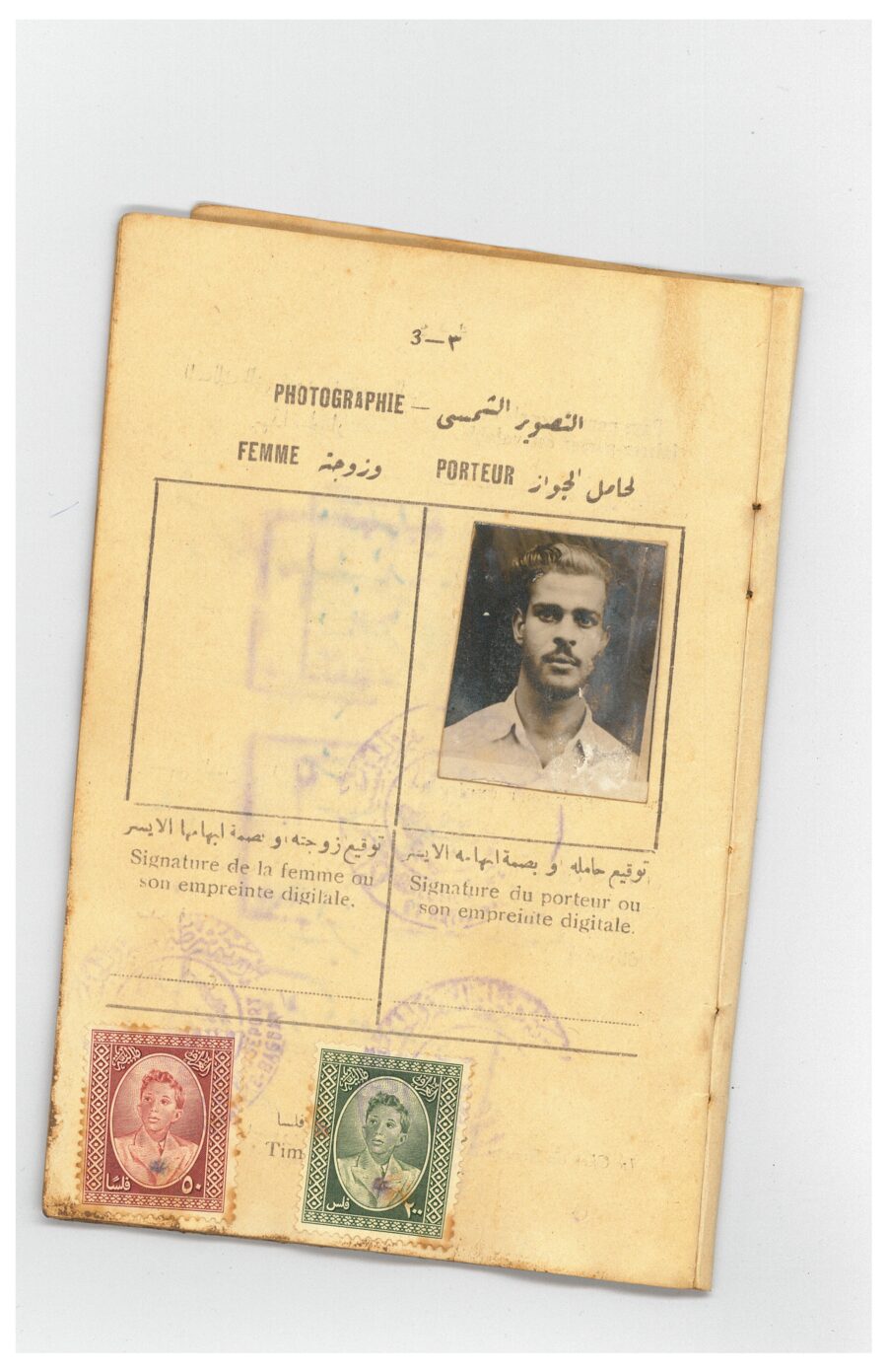 Photo page of Saba's Iraqi passport: a young man in an open collar as the bearer, with two Faisal II revenue stamps